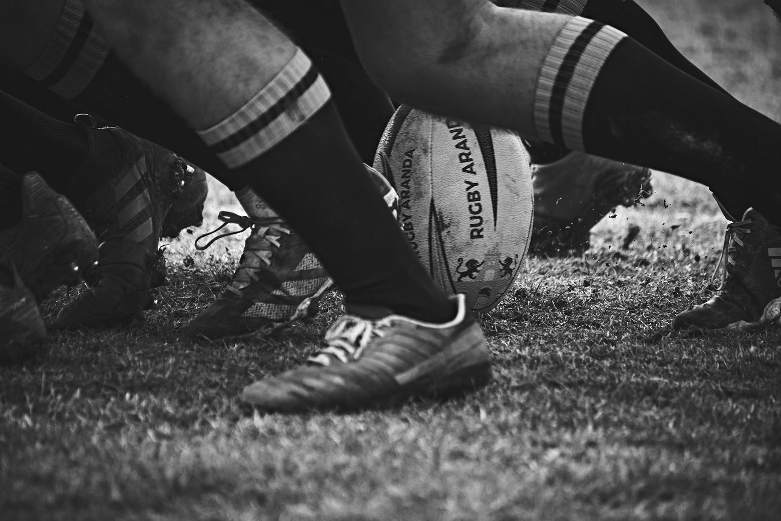 Rugby ball in scrum at ground level, black and white